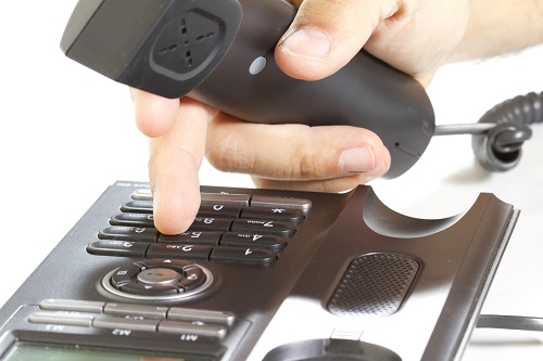 Closeup of fingers dialing on desk phone